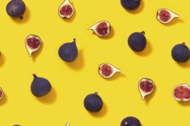 Taze incirler ve sarı arka planda dilimlenmiş incirler. Yemekler kusursuz. Yukarıdan bak. Düz yatıyordu