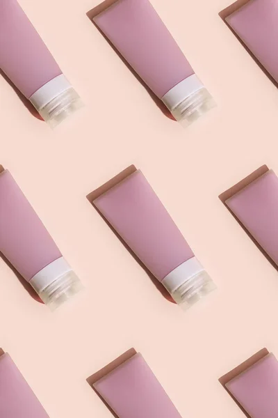 Pattern with Cosmetic tube for cream, gel, lotion. Beauty product package, mock up plastic container with hard shadows on pink colored background, monochrome image.