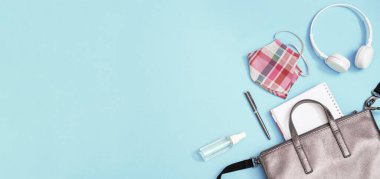 Okul malzemeleri ve kişisel koruyucu ekipmanlarla dolu gri deri bir sırt çantası. Yüz kalkanları, el dezenfektanı, fotokopi defterleri, kalemler. Okul konseptine geri dönelim. cjpy alanı olan pankart.