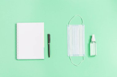 Okul, eğitim ve kişisel koruma gereçleri için kırtasiye malzemeleriyle yatıyordu. Yüz maskesi, el dezenfektanı, defter, kalem. Üst görünüm ve kopyalama alanı.