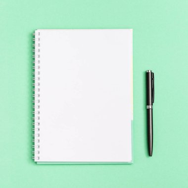 Temiz sayfası ve gri kalemi olan bir defter. Okul ve eğitim için kırtasiye malzemeleriyle yatıyordu. Üst görünüm, yeşil arkaplanda yakın plan.