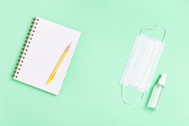 Okul, eğitim ve kişisel koruma gereçleri için kırtasiye malzemeleriyle yatıyordu. Yüz maskesi, el dezenfektanı, defter, kalem. Kopyalama alanı olan üst görünüm.