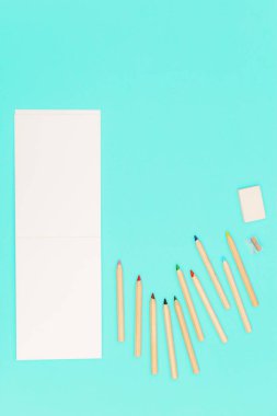 Renkli kalemlerle yatıp okul ve eğitim için çizim tahtası açtım. Ahşap renkli kalemler, kalem açacağı, silgi seti. Arkaplan sosyal medya tasarımı.