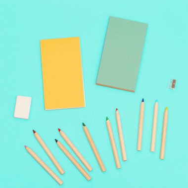 Yaratıcılık için renkli kalemlerin ve çizim defterlerinin üst görüntüsü. Ahşap renkli kalemler, kalem açacağı, silgi seti. Arkaplan sosyal medya tasarımı.