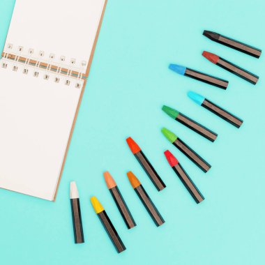 Pastel boya kalemleri ve çizimler için ilkbaharda açık bir defter. Sanatçının işyeri. Kopyalama alanı olan sosyal medya ve yaratıcılık arkaplanı.