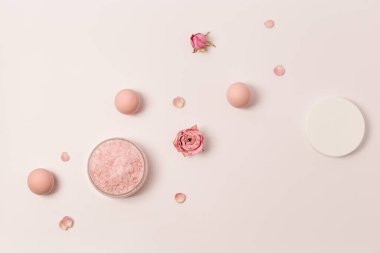 Kavanozda gül kokulu deniz tuzu, kep ve gül çiçekleri. Kozmetik ürünü üst görünüm, eğilim pembe pastel renkli, minimal düz yatış.