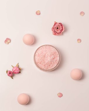 Kavanozda gül kokulu deniz tuzu, kep ve gül çiçekleri. Kozmetik ürünü üst görünüm, eğilim pembe pastel renkli, minimal düz yatış.