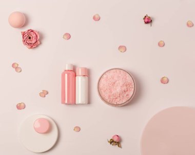 Gül kokulu deniz tuzu kavanozunda küçük şişeler duş jeli, sabun ve gül çiçekleri podyumda. Kozmetik ürünü üst görünüm, eğilim pembe pastel renkli, minimal düz yatış.