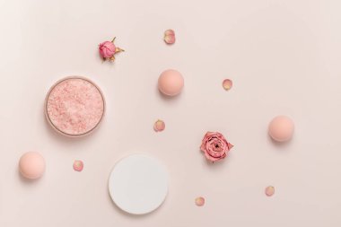 Aromatik deniz tuzu kristalleri ve gül yağı çiçeği. Kozmetik banyo ürünü üst görünümü olan spa kompozisyonu, pembe pastel renkli, asgari eğilim.