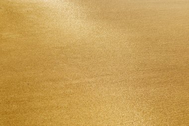 Kum dokusu. Altın kum. Islak kum parlak güneşte parlar. Seçici odak.