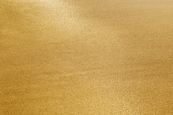Kum dokusu. Altın kum. Islak kum parlak güneşte parlar. Seçici odak.