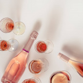 Rózsa bor választék kristály pohár, üveg rózsa pezsgő pezsgő pezsgő világos alapon. Nyári alkoholos ital tetejére néző, borászati koncepció.
