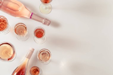 Birçok bardak gül şarabı ve köpüklü pembe şarap. Parti için hafif alkollü içecek. Yaz günü ışık masasında yatıyordu.. 