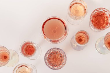Kristal bardaklarda gül şarabı, hafif arka planda gül şampanyası köpüklü şarap. Alkolik yaz içkisi üst görünüm, şarapçılık konsepti.