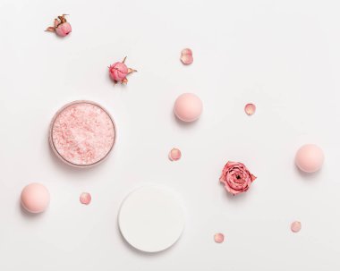 Kavanozda gül kokulu deniz tuzu, kep ve gül çiçekleri. Kozmetik ürünü üst görünüm, eğilim pembe pastel renkli, minimal düz yatış.