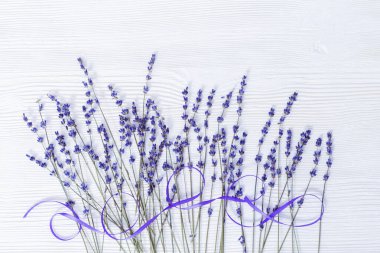 Beyaz ahşap arka planda lavanta çiçekleri ve kurdele. Ahşap üzerinde lavanta dalları.