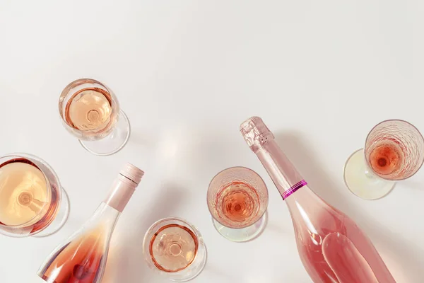 Rose wine assortment in crystal glasses, bottle of rose champagne sparkling wine on light background. Summer alcoholic drink top view, winetasting concept.