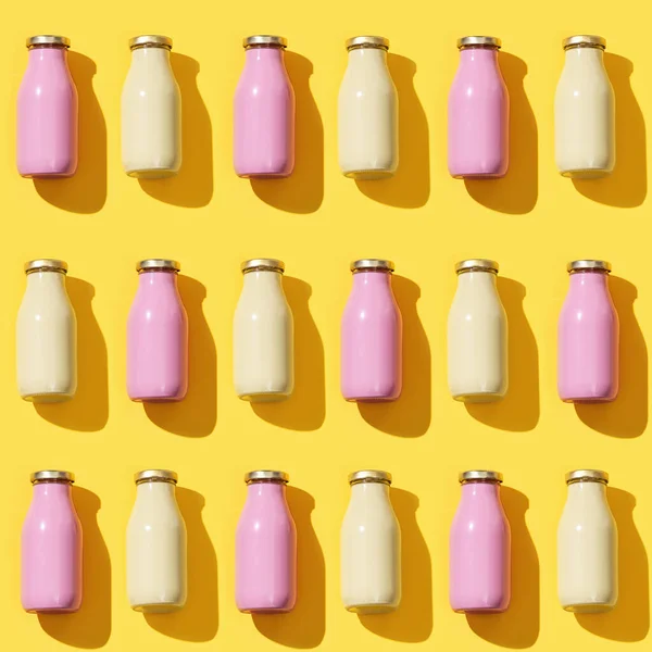 Pattern from small glass bottles for juice or yogurt, packaging template mock up on yellow colored background. Dark shadow.