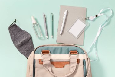 Okul gereçleri, yüz maskesi ve el dezenfektanı, okul rozeti, defterler, kalemler, okula dönüş konsepti..