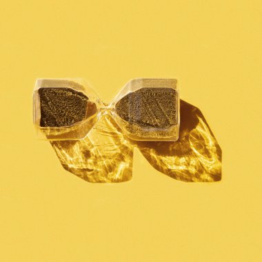 Süslü kum saatleri, damlayan altın yuvarlak parçacıklar, zaman kavramı, son dakika. Sarı arka planda kum saati ve sert gölge..