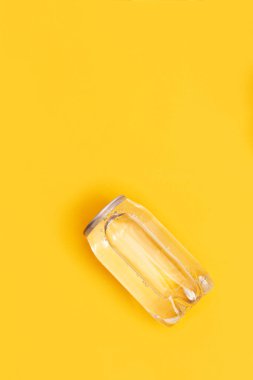 Sarı arka planda şeffaf su kutusu. Monokrom görüntüsü. Yaratıcı fikir, plastik şişede temiz su paketi. Üst görünüm.