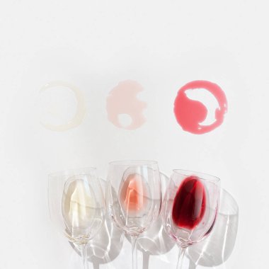 Güzel gölgeli bardaklarda şarap seti. Kırmızı, gül ve beyaz şaraplı bir arka plan. Sert ışık. Üst görünüm.