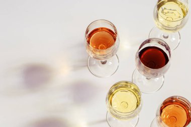 Güzel gölgeli bardaklarda şarap seti. Kırmızı, gül ve beyaz şaraplı arka plan fotokopi alanı. Sert ışık. Üst görünüm.