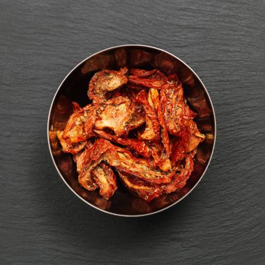 Kurutulmuş domatesler, İtalyan otları ve baharatlarıyla koyu arka planda fotokopi alanı, üst manzara. Ev yapımı kurutulmuş sebze..