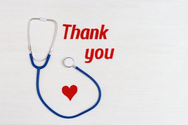 Stetoskop mavi, kırmızı kalp ve metin beyaz ahşap arka planda fotokopi alanı ile birlikte teşekkürler. Sağlık ve tıbbi konsept. Dünya Sağlık Günü. Yukarıdan görüntüle.