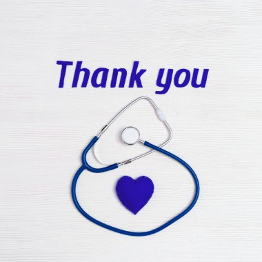 Stetoskop mavi renk, kalp ve metin beyaz ahşap arka planda fotokopi alanı ile teşekkür ediyor. Tıbbi personel için şükranlarımı sunuyorum. Ulusal Hemşireler Günü. Üst görünüm.