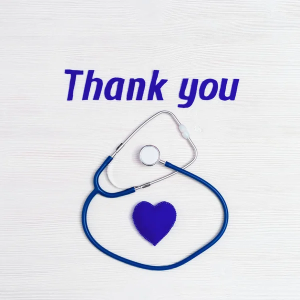 Stetoskop mavi renk, kalp ve metin beyaz ahşap arka planda fotokopi alanı ile teşekkür ediyor. Tıbbi personel için şükranlarımı sunuyorum. Ulusal Hemşireler Günü. Üst görünüm.