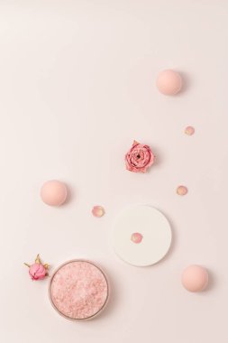 Kavanozda gül kokulu deniz tuzu, kep ve gül çiçekleri. Kozmetik ürünü üst görünüm, eğilim pembe pastel renkli, minimal düz yatış.