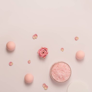 Kavanozda gül kokulu deniz tuzu, kep ve gül çiçekleri. Kozmetik ürünü üst görünüm, eğilim pembe pastel renkli, minimal düz yatış.