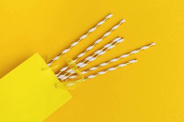 Kağıt paketin içindeki kokteyl için kağıt kamışlarla yakın çekim sarı kompozisyon. Parti, tatil, doğum günü konsepti. Üst görünüm ve düz uzanma.