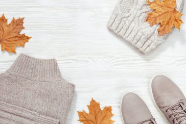Sonbahar rahat giysiler. Sıcak bir ceket, süet gri çizmeler, beyaz ahşap arka planda örülmüş bir şapka. Kadın kıyafetleri. Sıradan moda kıyafetleri. Düz yatıyordu. Üst Görünüm.