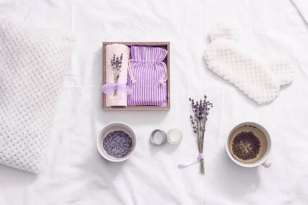 Wellness gift box with healthy herbal lavender tea, scent of lavender improves sleep and alleviates insomnia. Sleep mask and balsam with essential oil on white bedclothes.