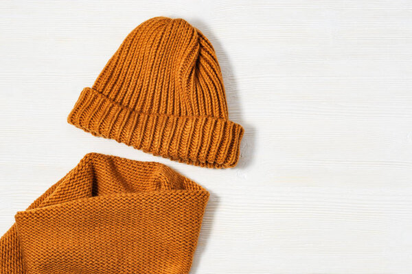Handmade knitted clothing, woolen hat and soft snood ginger colour. Warm things for winter season. Top view. Copy space. Flat lay.