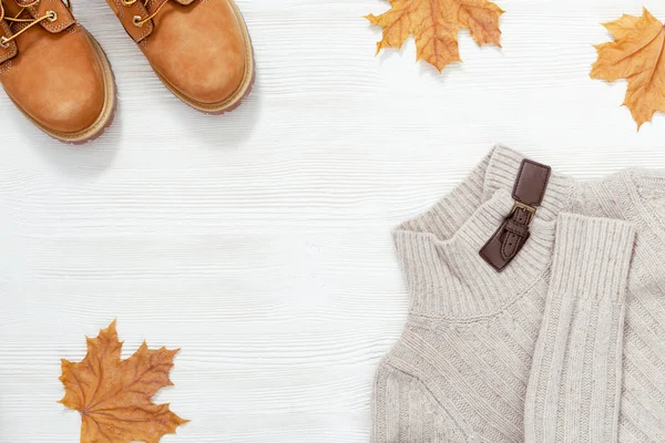 女性秋装 时尚橙色羊皮靴 温暖的针织套头衫装饰秋天枫叶 平铺着舒适的衣服 把空间复制到白色的木桌上 — 图库照片