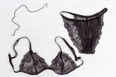 Siyah dantelli sütyen ve külot, beyaz ahşap arka planda. Kadın moda aksesuarları. Kadın iç çamaşırları. Üst görünüm.