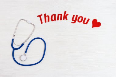 Tıbbi steteskop, kırmızı kalp ve metin fotokopi alanı olan beyaz ahşap arka planda teşekkürler. Sağlık sigortası konsepti. Ulusal Hemşireler Günü. Üst manzara, düz uzanma.