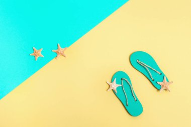 Plaj tatili kavramı. Plaj terlikleri ve parlak kağıtta küçük deniz yıldızları. Kopyalama alanı olan yaz düzlüğü.