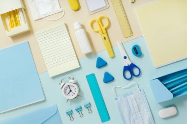 Ders çalışmak ve çalışmak için defter ve kırtasiye malzemesi, antiviral yüz maskesi ve el dezenfektanı, zaman kontrolü için çalar saat. Okula geri dönmek yeni, yaratıcı, normal konsept. Eğitimsel üst görünüm güvertesi.
