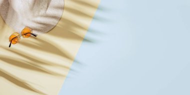 Geniş kenarlı şapkalı yaz arkaplanı, kumlu arka planda renkli güneş gözlüğü, güneş gölgeleri ve fotokopi alanı. Yaz konsepti pastel renkli estetik fotoğraf.