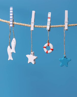 Deniz hayatı dekorasyonlu deniz konsepti mavi arkaplanlı ipte asılı duruyor. Deniz oyuncakları cankurtaran halatı, seastarlar ve kopya alanı olan küçük balıklar..