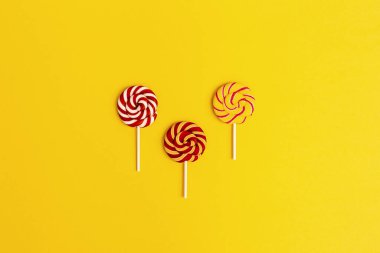 Çubuğun üzerinde renkli şeker lolipopları. Parlak renklerle minimum yaşam bileşimi. Sağlıksız gıda konsepti. Düz yatıyordu.