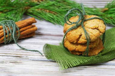 Tahta arka planda çam dallarıyla süslenmiş zencefilli kurabiye ve tarçın çubukları yığını. Boşluğu kopyala.