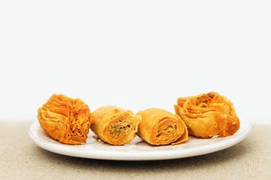 Geleneksel Doğu tatlıları, beyaz tabakta doğranmış fındık ve bal şurubuyla yakın plan çekimler. Seçici odaklanma. Çerçevenin üstüne boşluk kopyala