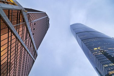 Camdan yapılmış mavi renkli modern binaların manzarası. İki yüksek ev ve mavi gökyüzü. Cennete kadar uzanan yüksek binalar. 