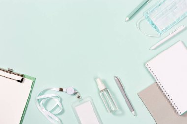 Okul aksesuarları, yeni normal kavram, tıbbi maske ve naneli kağıt arka planda el dezenfektanı. Kapat, üst görünüm.