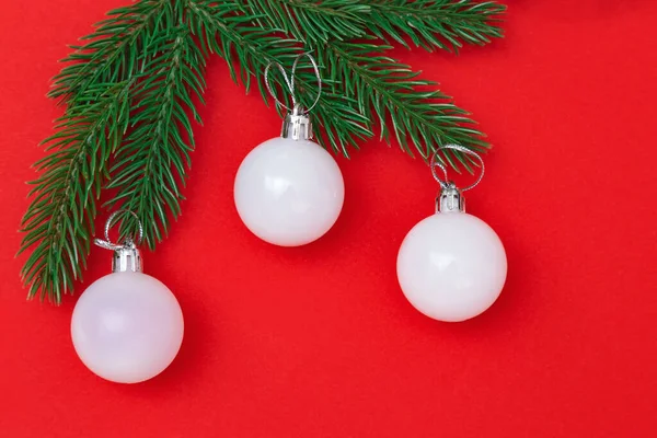 Tři Bílé Vánoční Skleněné Koule Zelených Větvích Červeném Pozadí Novoroční — Stock fotografie
